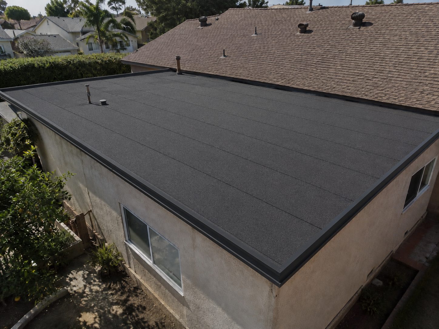 The same flat roof deck finished with a new black torch-down membrane and clean seams