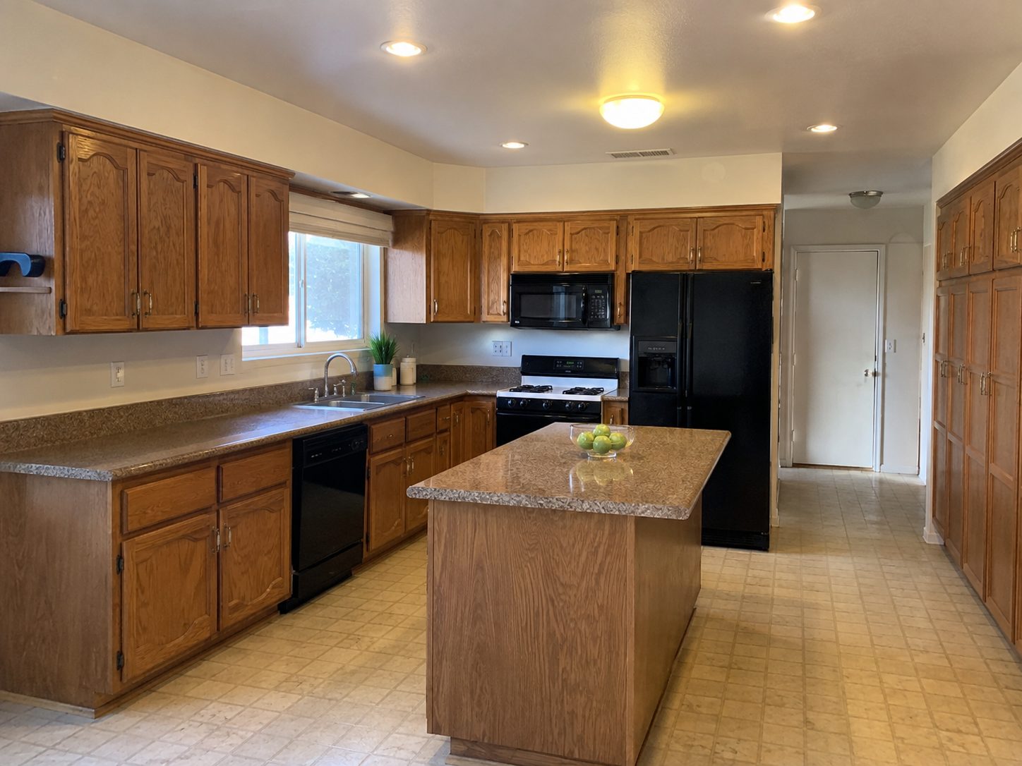 Kitchen with oak cabinets, laminate countertops, and a black refrigerator before remodeling
