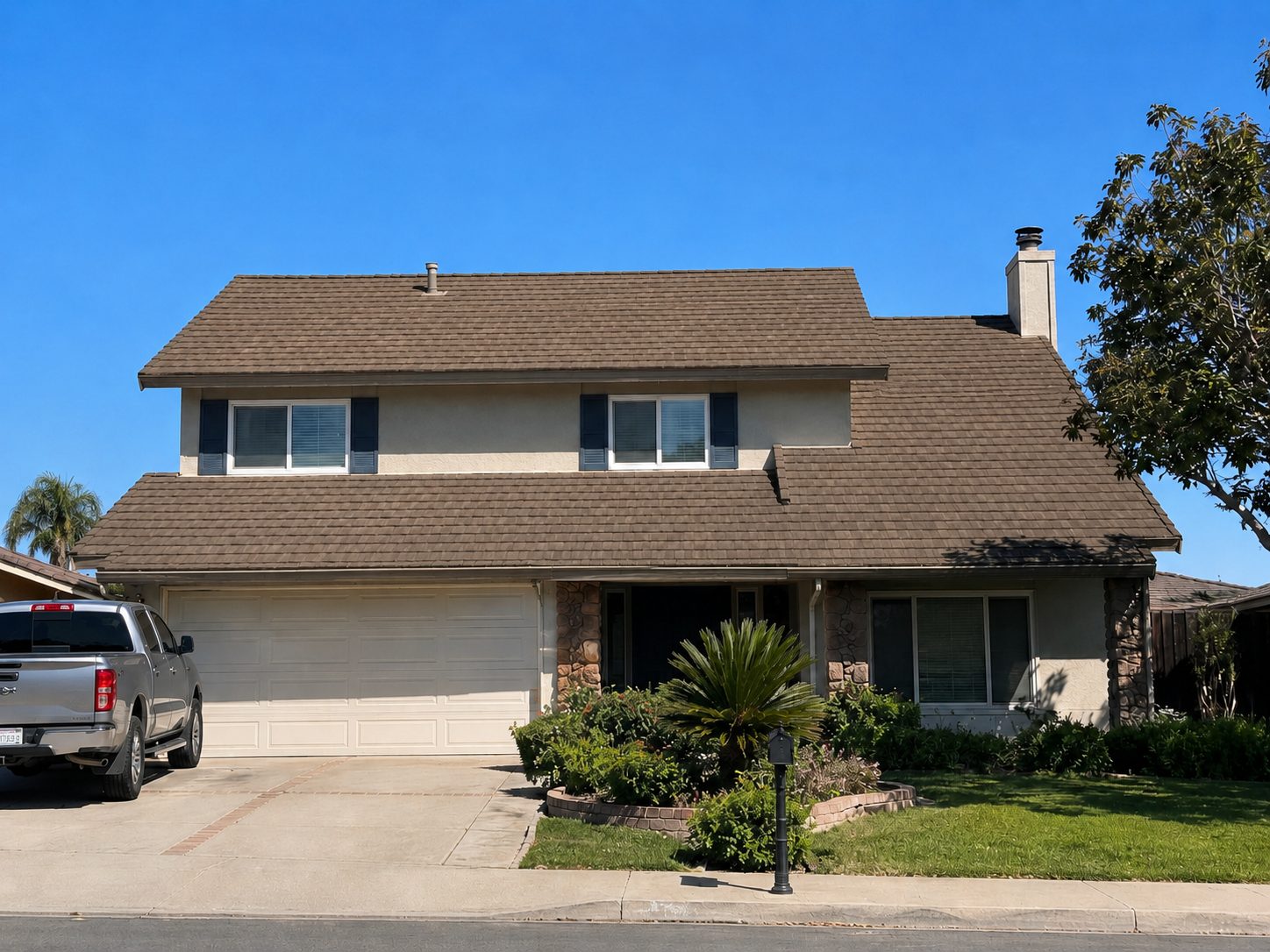 The same gable elevation covered in new brown architectural shingle