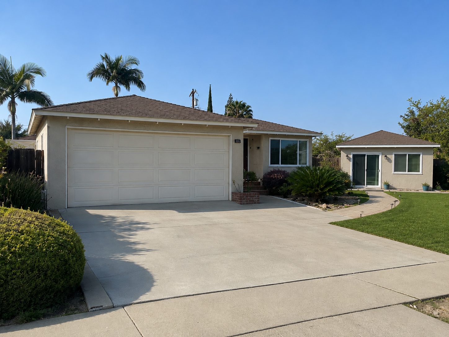 The same frontage with lawn in place of the rock garden and a detached ADU with a glass door standing beside the house