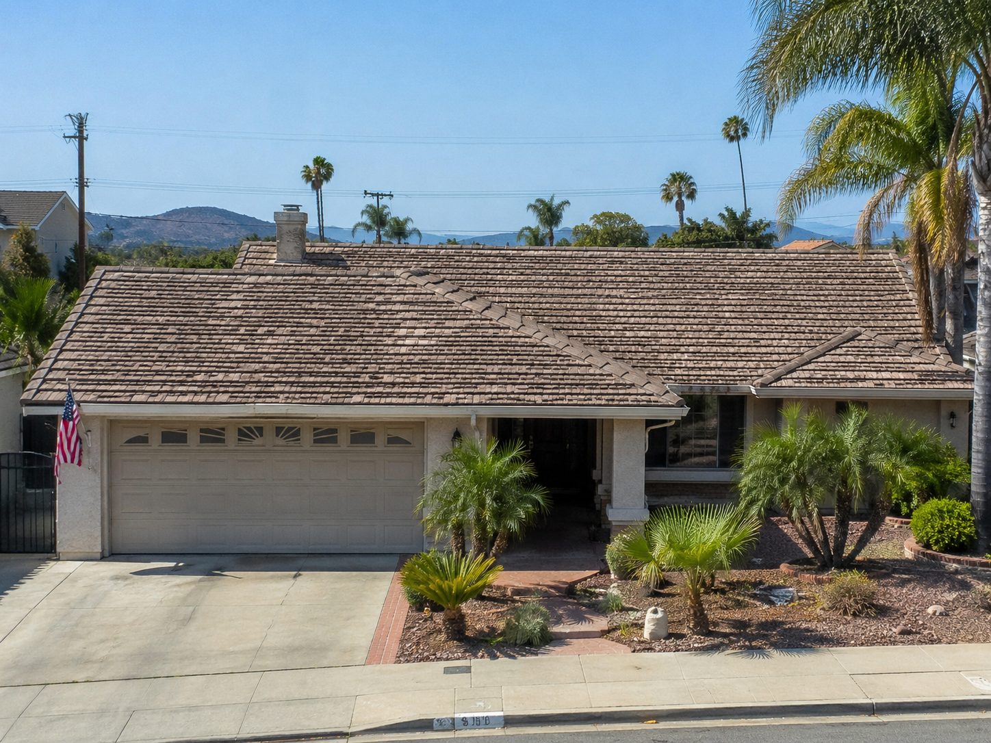 Weathered beige concrete tile roof with faded and chipped tiles along the hip elevation