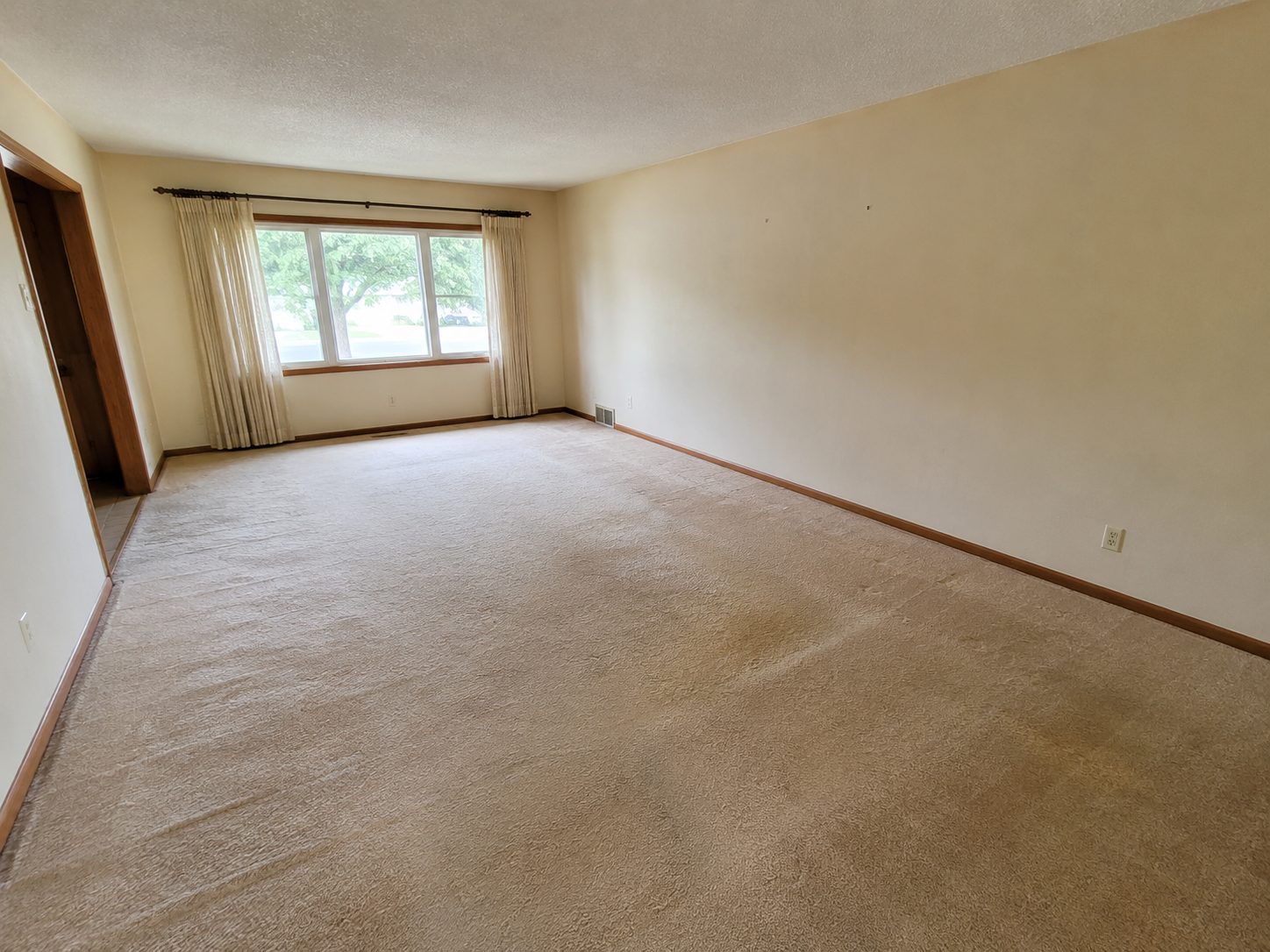 Living room with old beige carpet across the full floor