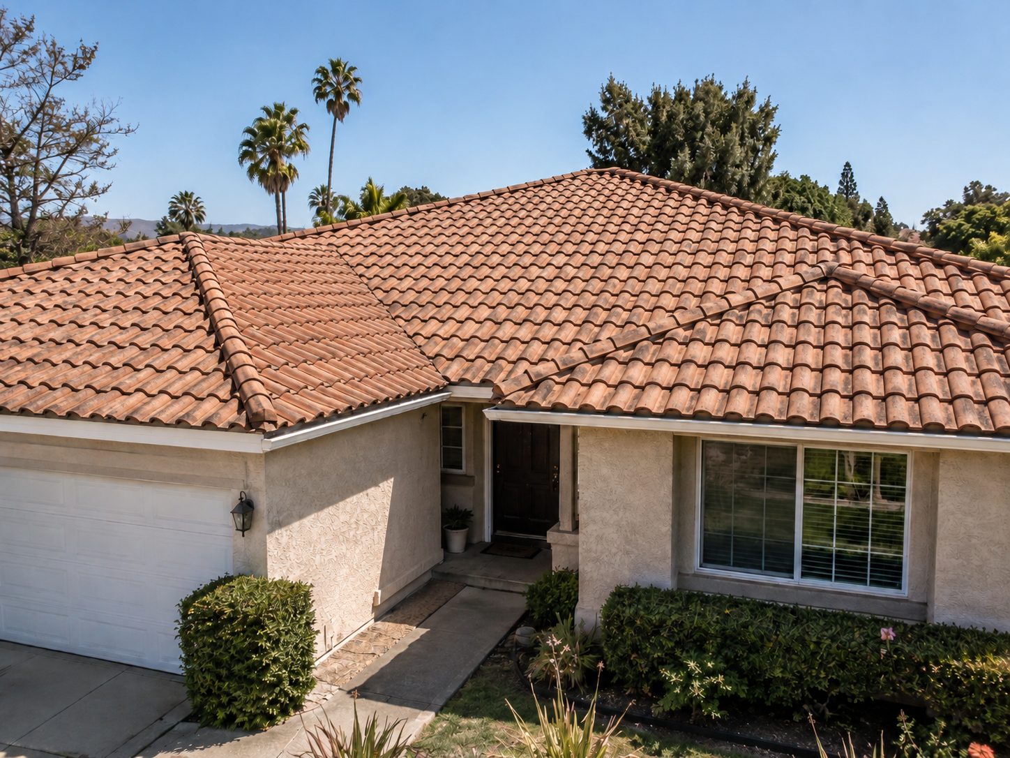 Single story stucco house with a new terracotta clay barrel tile roof over the main house and garage, with fresh ridge caps and clean eave lines