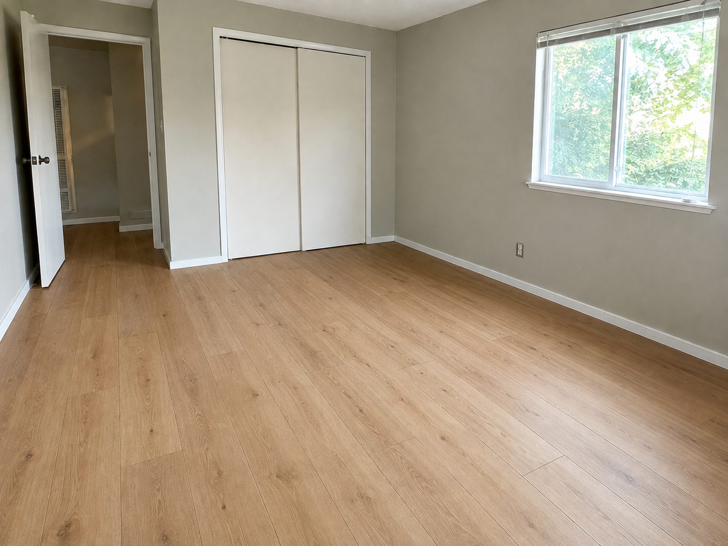The same bedroom with light oak plank flooring and refitted baseboards