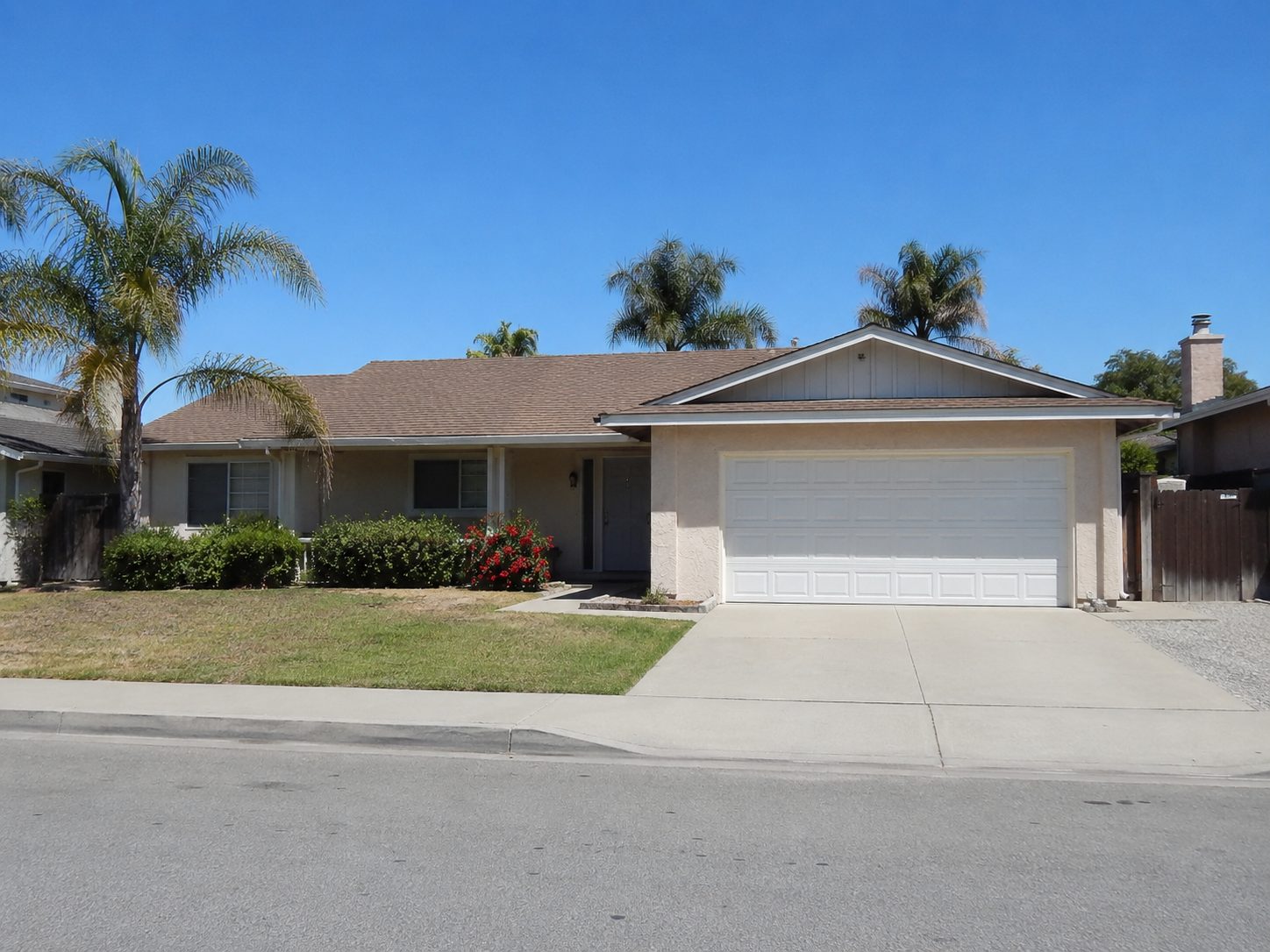 Street view of a single storey house with a white two car garage door at the right end of the elevation