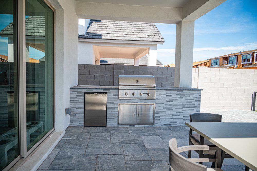 Built-in outdoor kitchen with grill and stone surround by Dreamliner Construction
