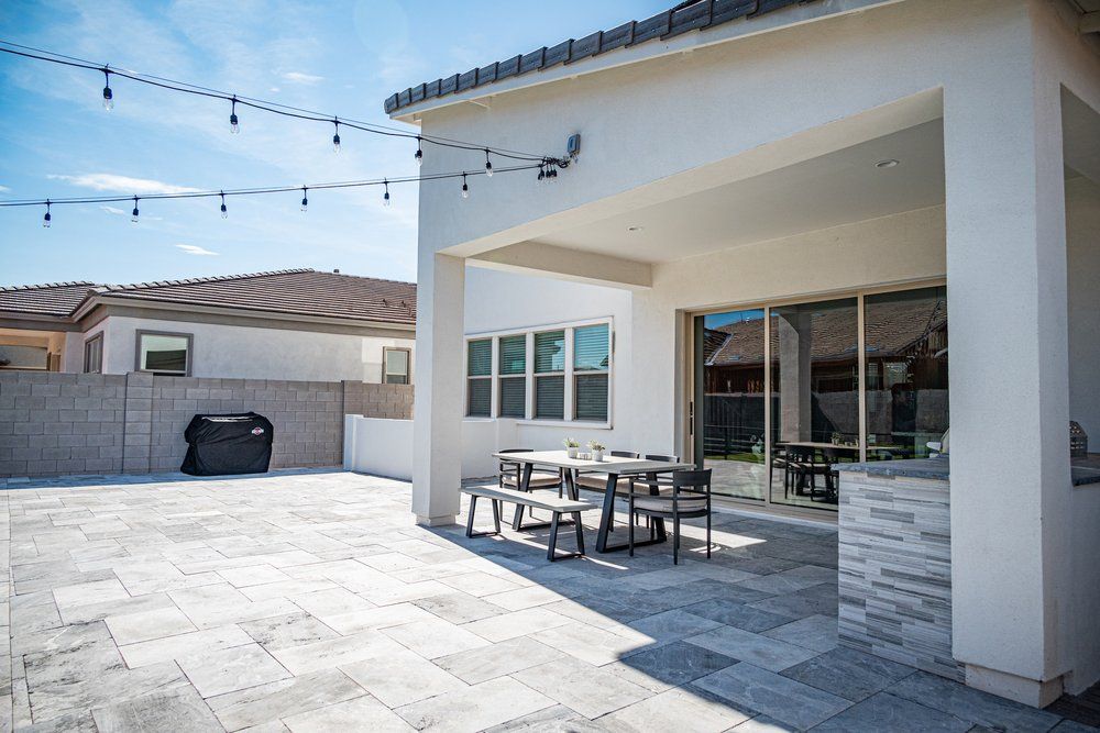 Covered patio with string lights and outdoor dining by Dreamliner Construction